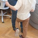 Warsztaty rodzinne "Poznajemy emocje z Kamą Lamą" - dziecko wykonuje ćwiczenie ruchowe wspólnie z osobą dorosłą, unosząc nogę i naśladując prezentowany ruch.