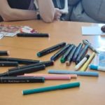 Terapia ręki - konsultacje - dzieci podczas zajęć przy stole wykonują prace plastyczne z wykorzystaniem kolorowych flamastrów i materiałów edukacyjnych.