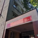 Wejście do Poradni Psychologiczno-Pedagogicznej nr 3 w Warszawie - zdjęcie czerwonej tablicy informacyjnej .