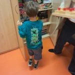 Dziecko wybierające grę edukacyjną z szafki w gabinecie poradni.
