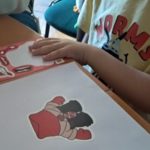 Warsztaty rodzinne "Poznajemy emocje z Kamą Lamą" - dziecko podczas zajęć dopasowuje elementy przedstawiające części twarzy do ilustracji postaci.